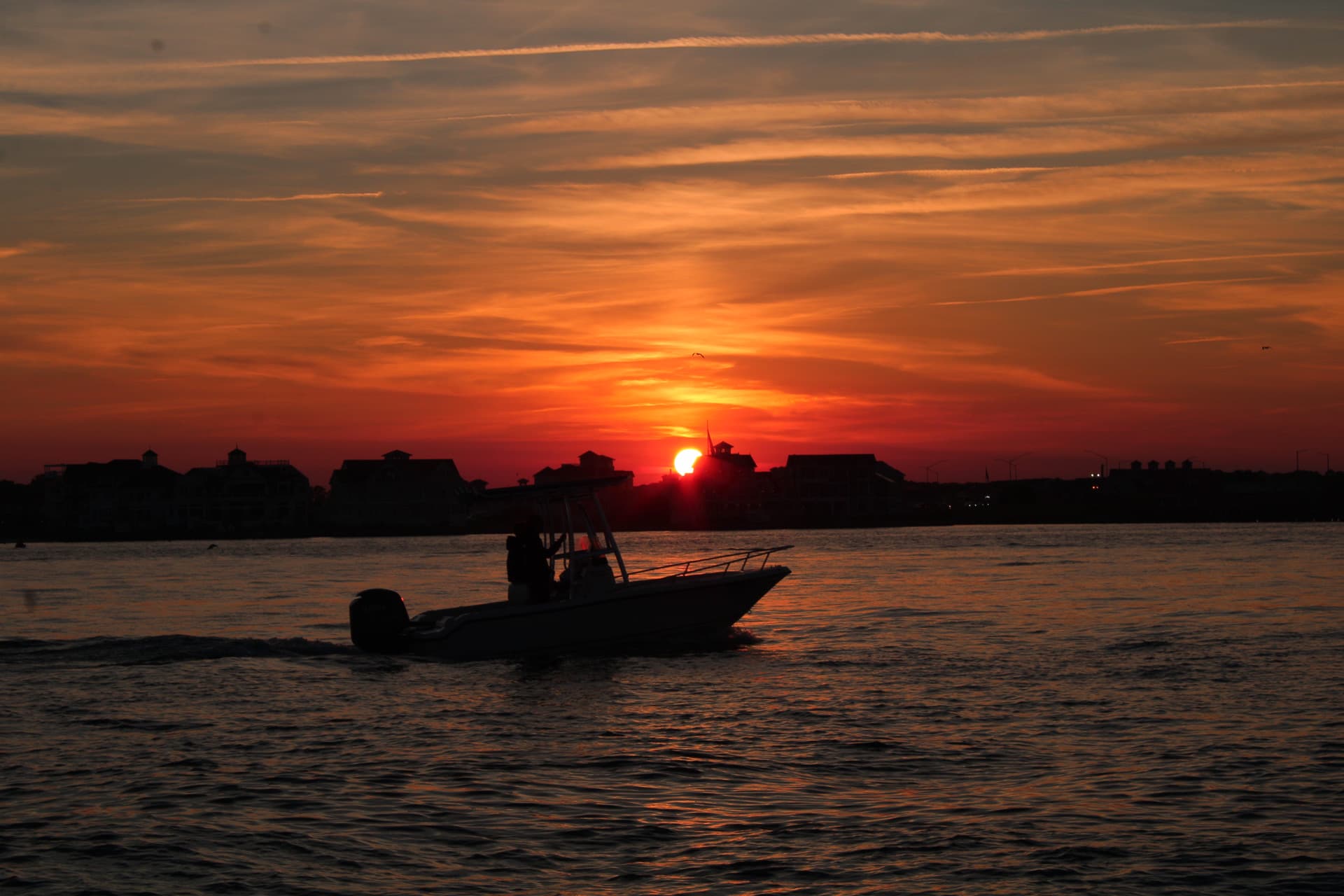 A silhouette of a boat going by in the OC bay as the sun sets.