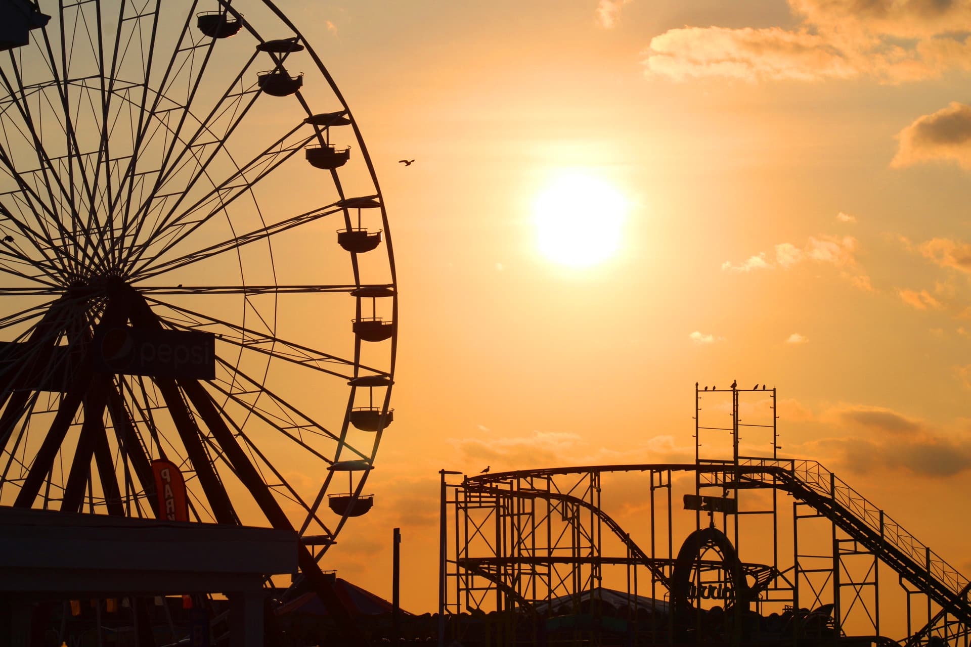 A golden sunrise with the silhouette of Jolly Roger Amusement park in OC, MD.