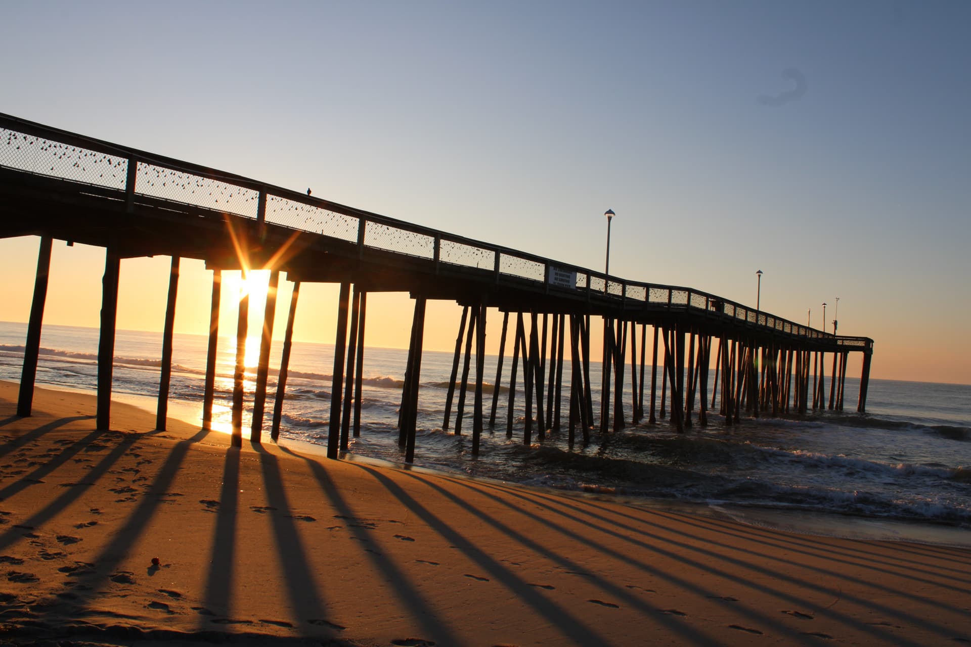 A shiny sunrise peeking through the pier in OC, MD.